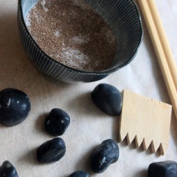 Tools for making Zen Garden Soap: soap stones, handmade "sand'" rake, and a bowl of pumice, bentonite clay, and jojoba seed powder.